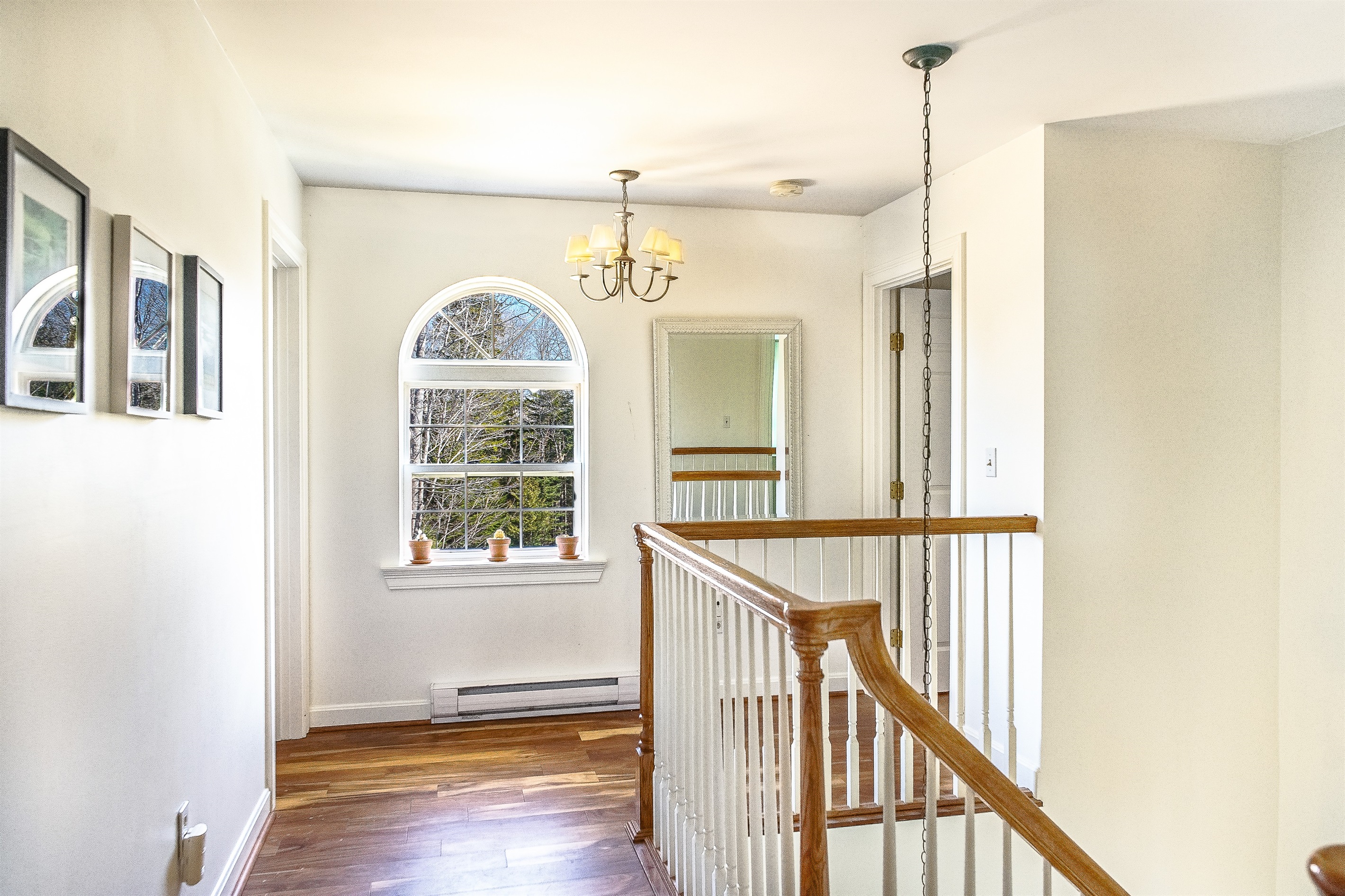 The sunlit right wing of the second floor leads to the private Primary Suite and the flexible dual twin guest room. This landing features bright windows and elegant hardwood floors, maintaining the home's airy atmosphere on the "Quiet Side."