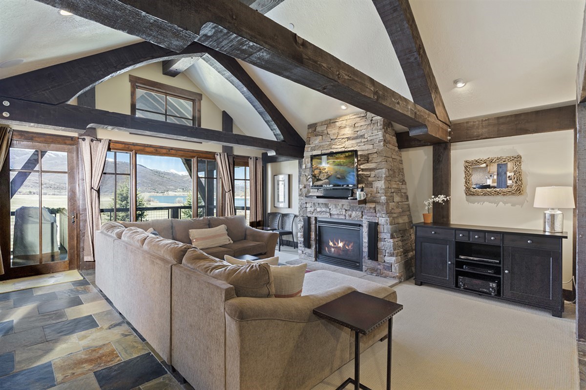 A cozy yet refined living area featuring a gas fireplace and expansive windows that flood the space with natural light and showcase the surrounding scenery.