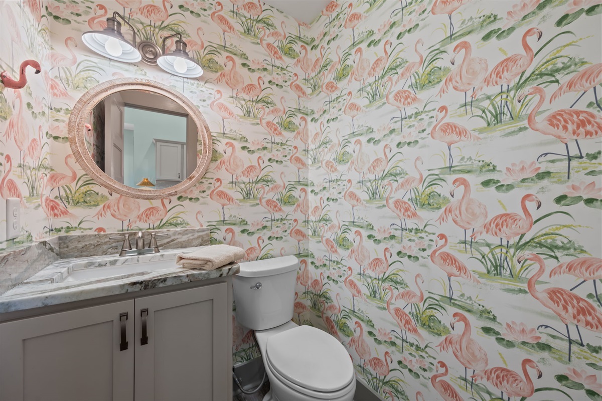 Stylish Powder room, featuring a marble vanity and fun coastal wallpaper
