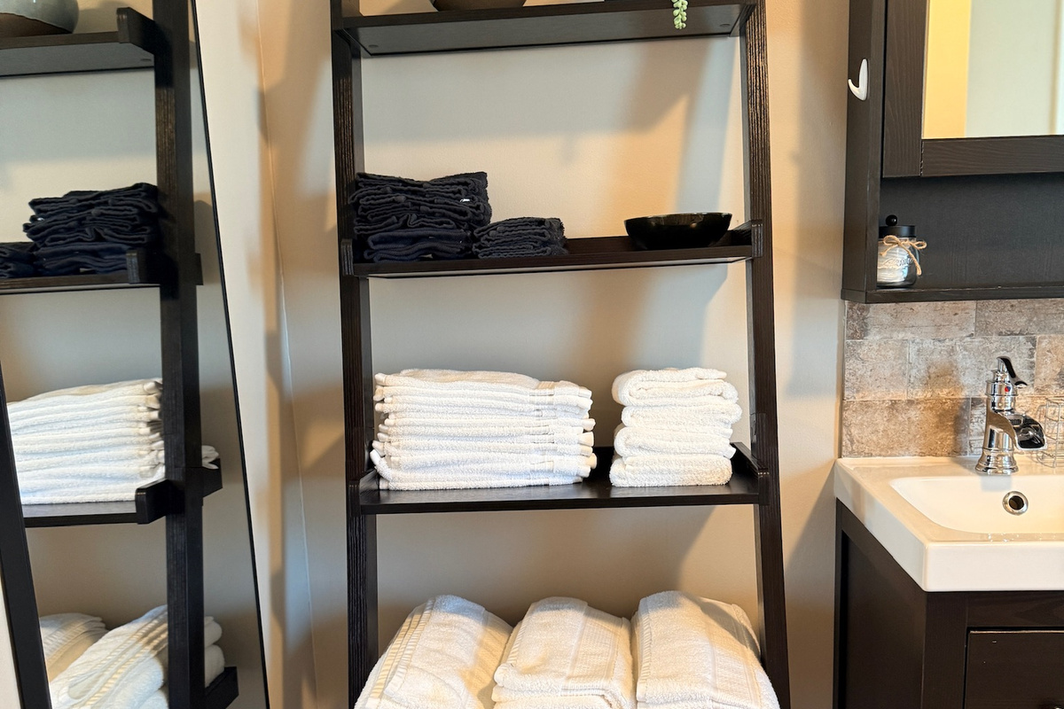 Open bathroom shelving stocked with fresh towels.