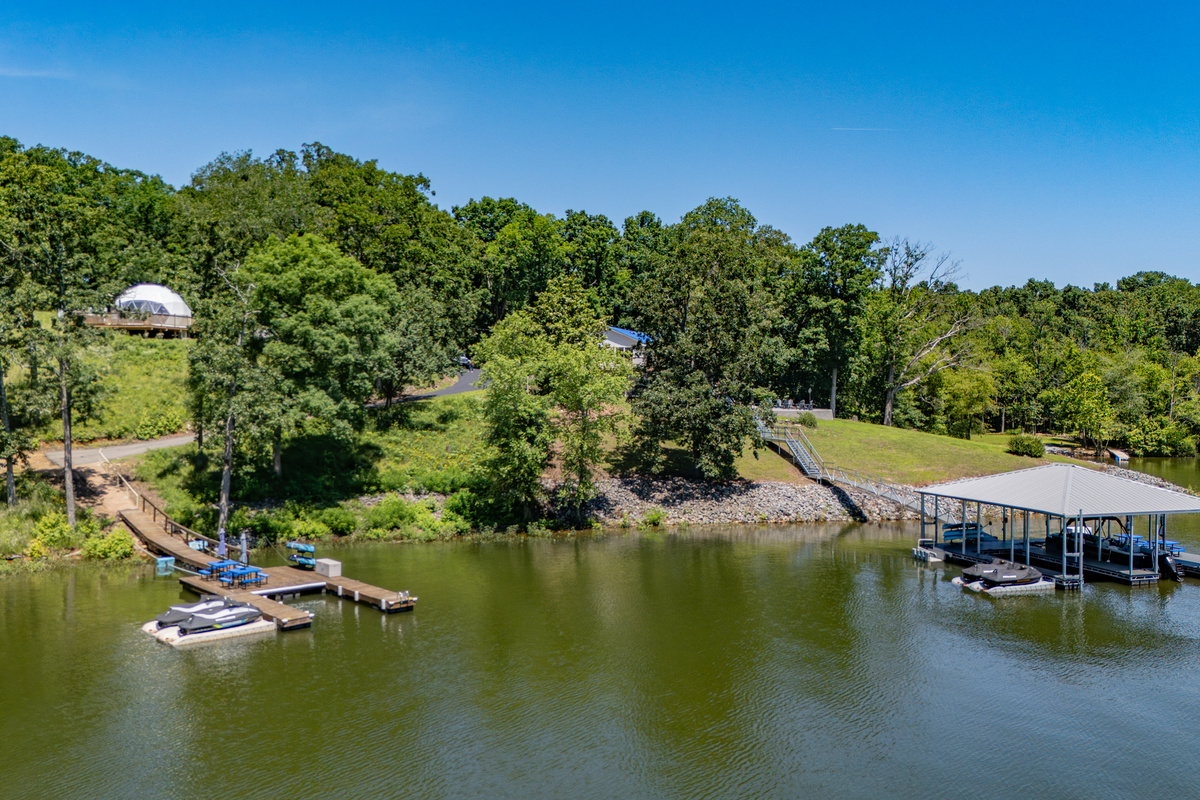Aerial view of The View’s shoreline and private dock; the white Anchor Dome next door is visible beyond the trees.