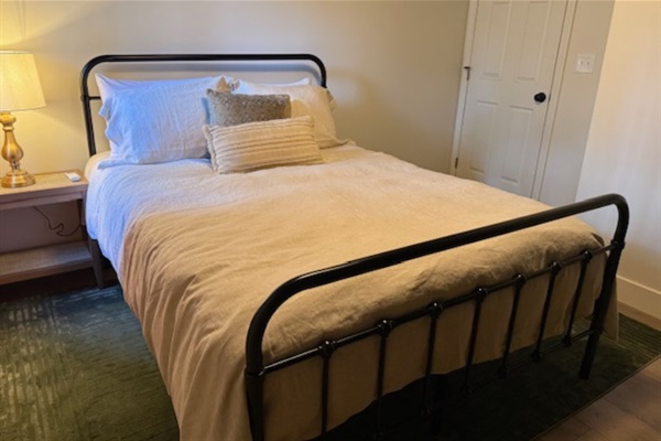 Comfortable queen bedroom with fresh linens, closet for hanging clothes, and a sound machine for a restful stay.