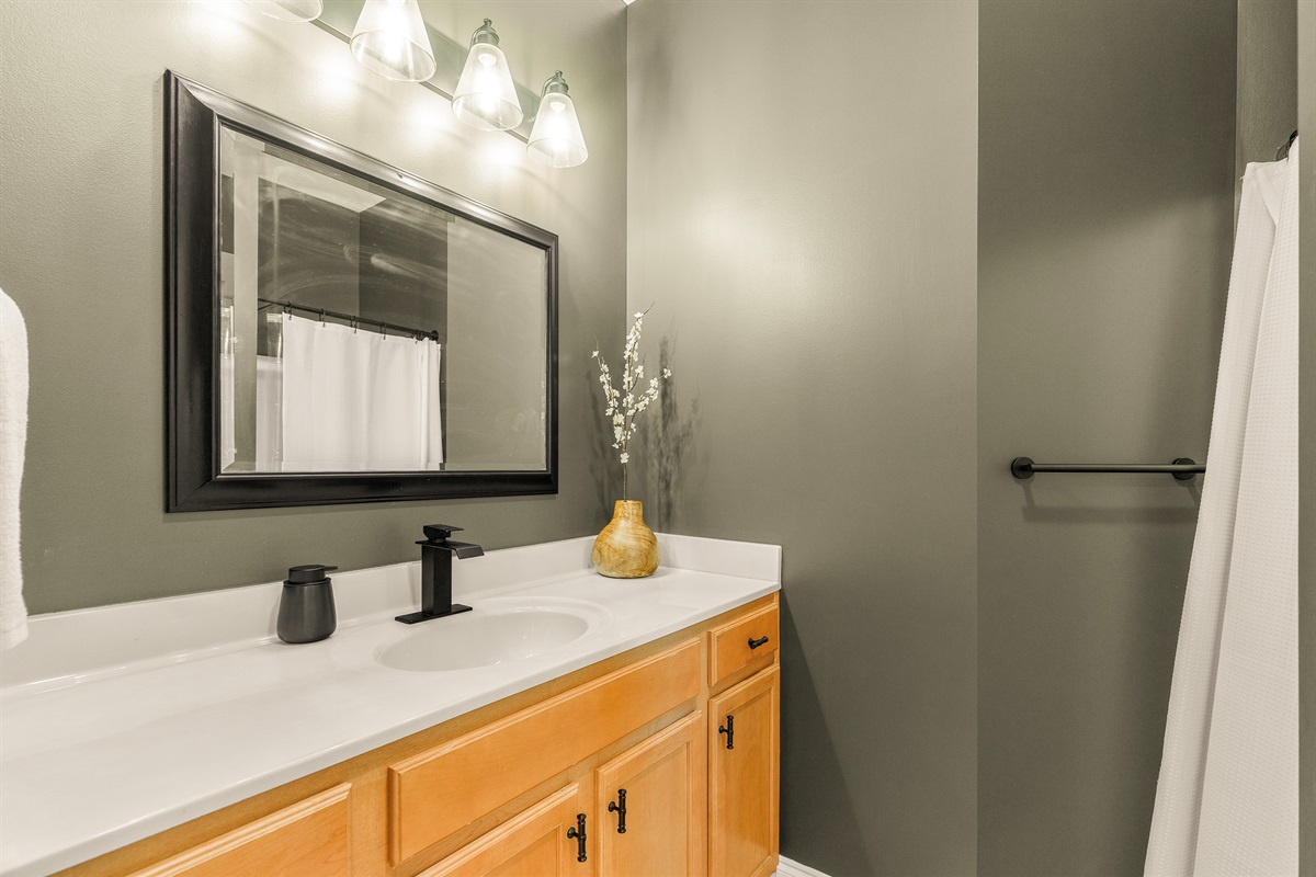 Earthy elegance meets updated style. A moody bronze finish sets the tone, with new matte black fixtures and a bright, solid-surface vanity—private, modern, and soothing