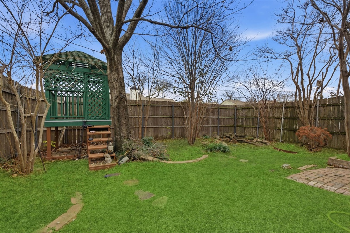 Fully fenced backyard with a raised gazebo, outdoor seating, high privacy fencing, and open space to relax or enjoy fresh air.