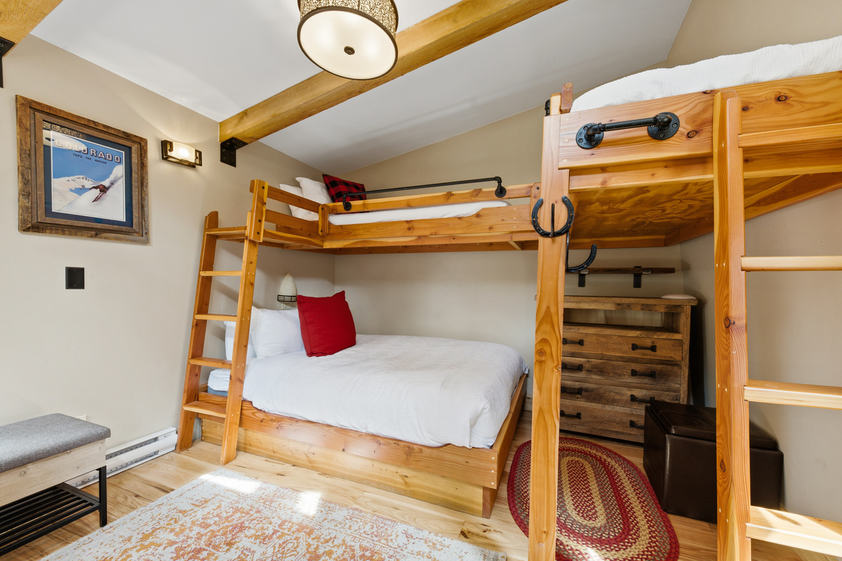 Backyard bungalow with twin-over-queen bunk and twin loft bed. Tv not seen in front corner. Bungalow is heated with a deadbolt door in a fenced backyard. 