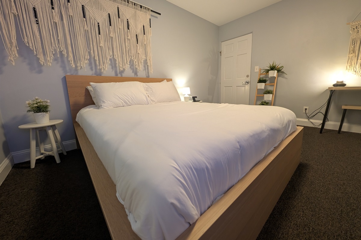 Guest bedroom with queen bed, desk and smart tv