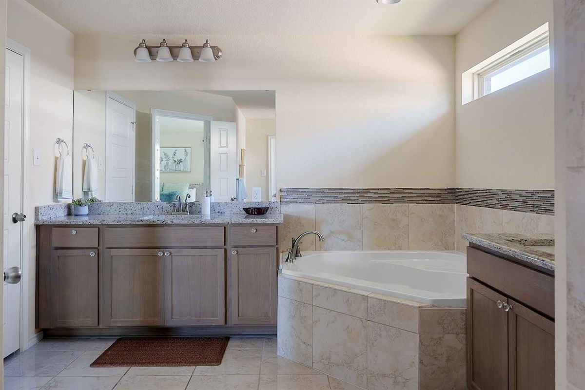 Explore this stylish bathroom featuring a large vanity, a luxurious soaking tub, and tasteful tile accents.