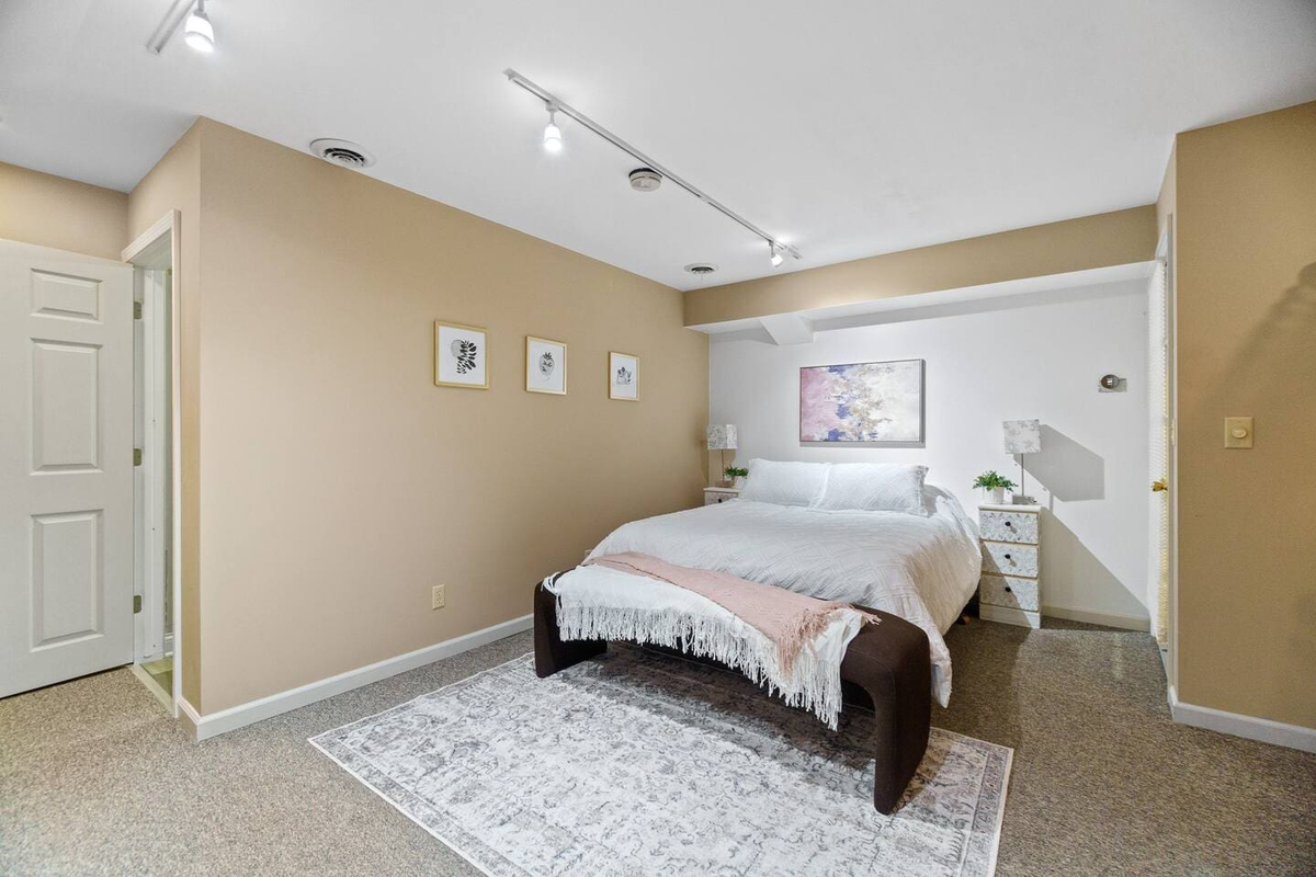 Cozy queen-sized bedroom with a soft carpet and bedside drawers, offering comfort and convenient storage for a relaxing stay.