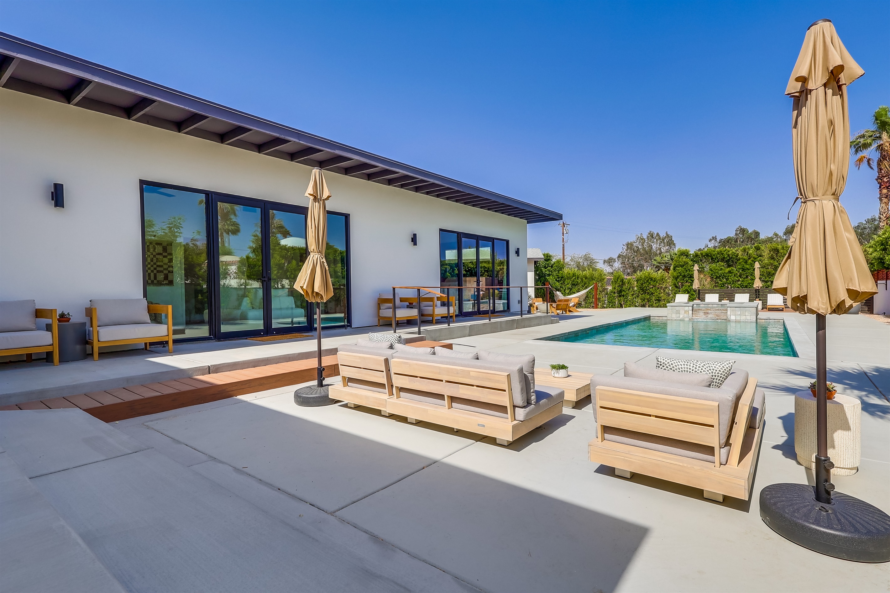 Outdoor space with several seating areas, pool chaise loungers