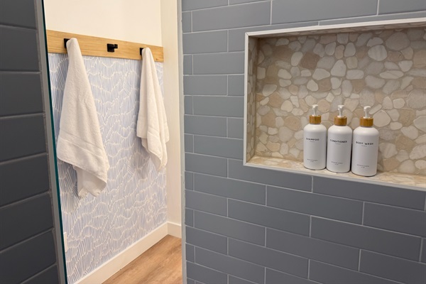 Beautifully tiled seamless walk-in shower located in bunk room suite