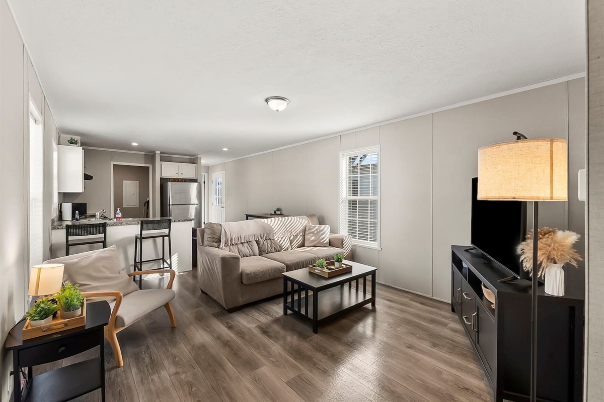 Bright and cozy living room with comfortable seating, smart TV, and open layout—perfect for relaxing stays.