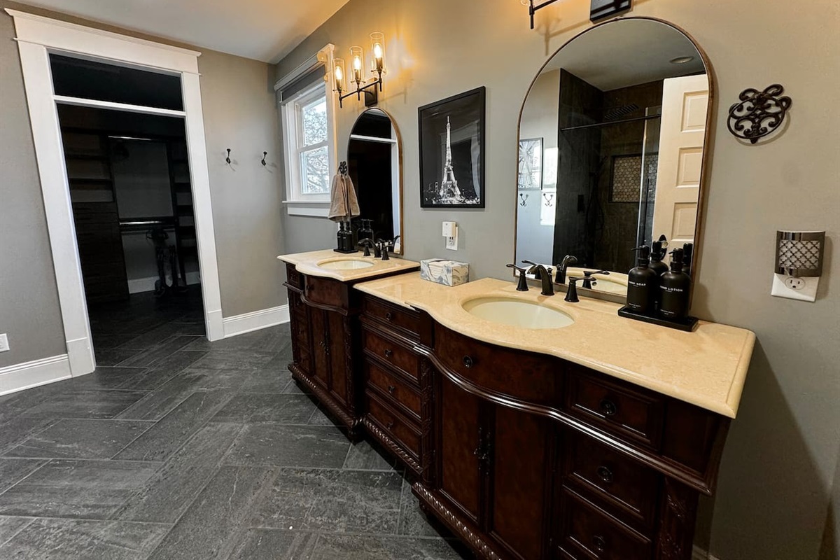 Double vanity in large Paris ensuite bathroom connects to oversized walk-in closet with built-ins.