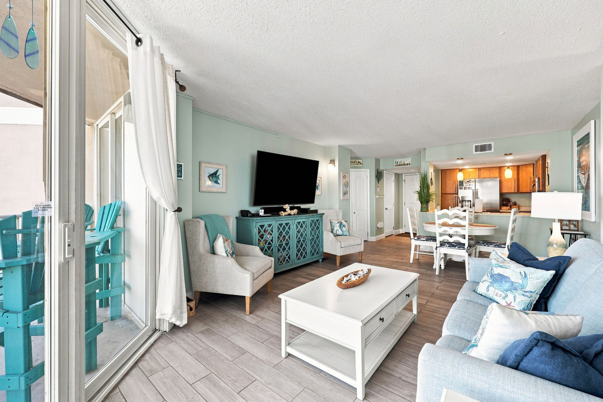 Relax and take in the view from this comfortable living room, featuring coastal blue decor and light-filled patio doors.