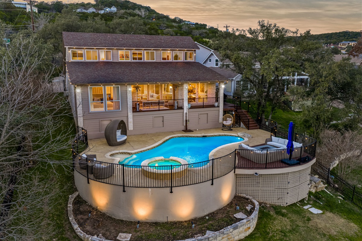 Elevated backyard pool and spa with glowing evening ambiance and scenic Hill Country views.