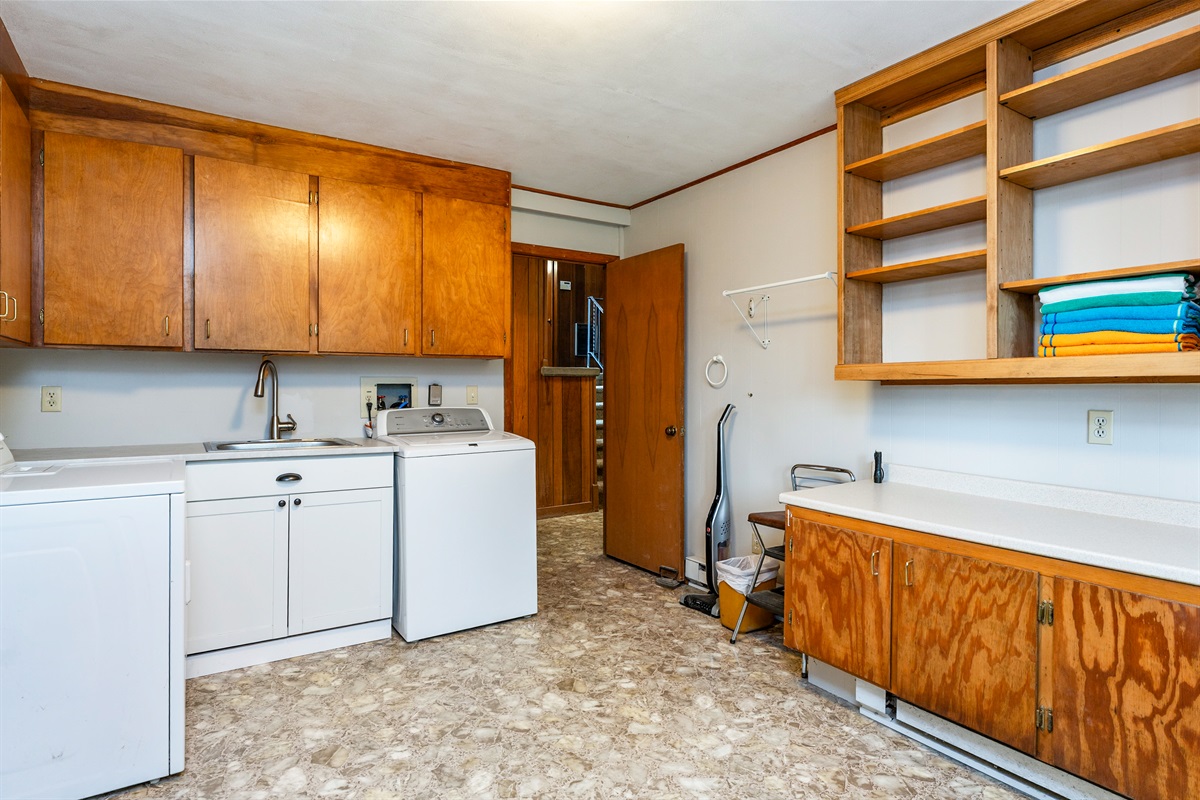 Spacious laundry room with ample cabinetry, utility sink, and washer/dryer setup for everyday convenience