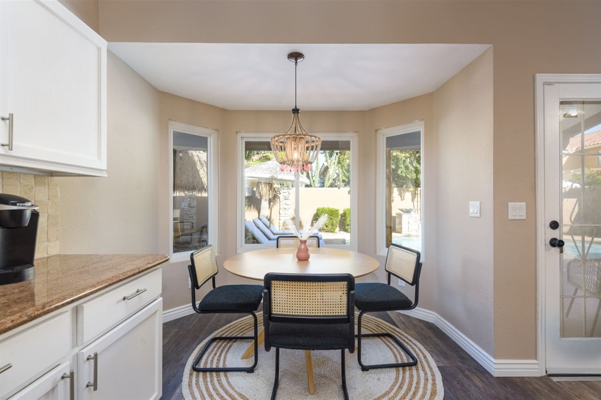 Dining nook with round table seating, bay windows, and views out to the pool area for meals or morning coffee.