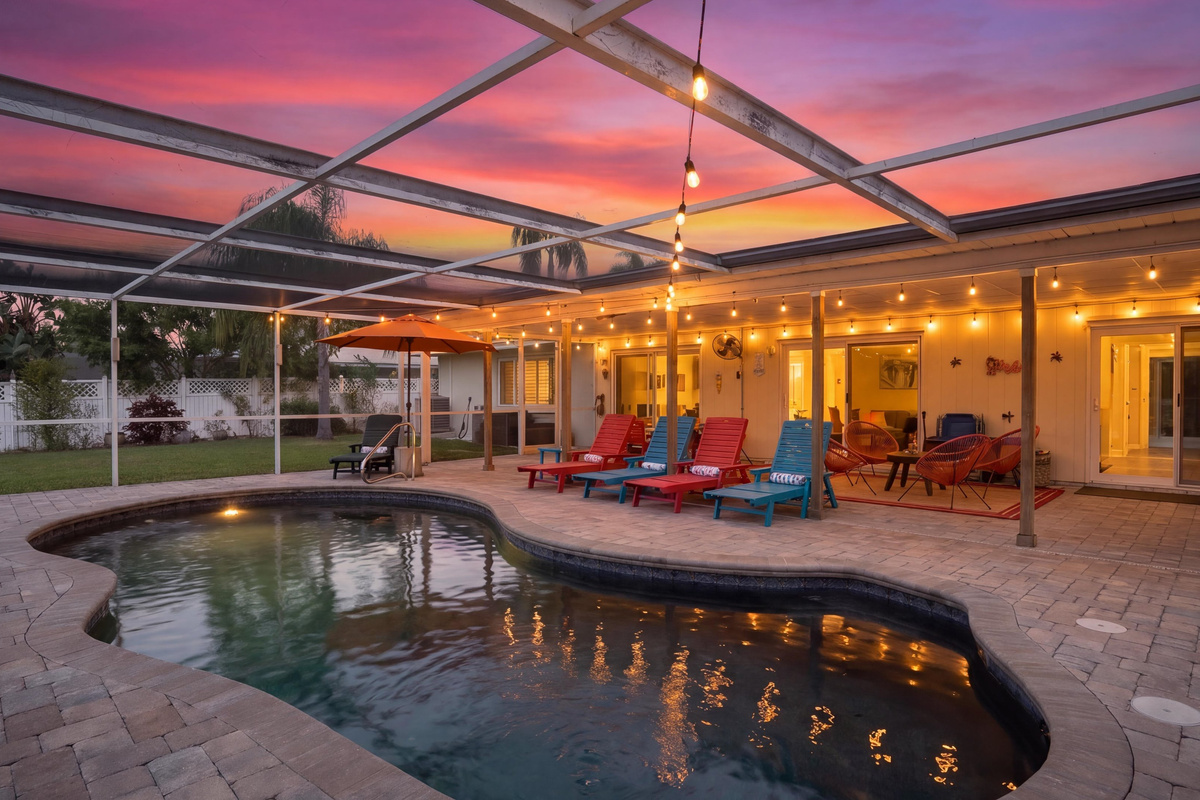 Colorful sunset skies illuminate the pool and inviting outdoor lounge area.