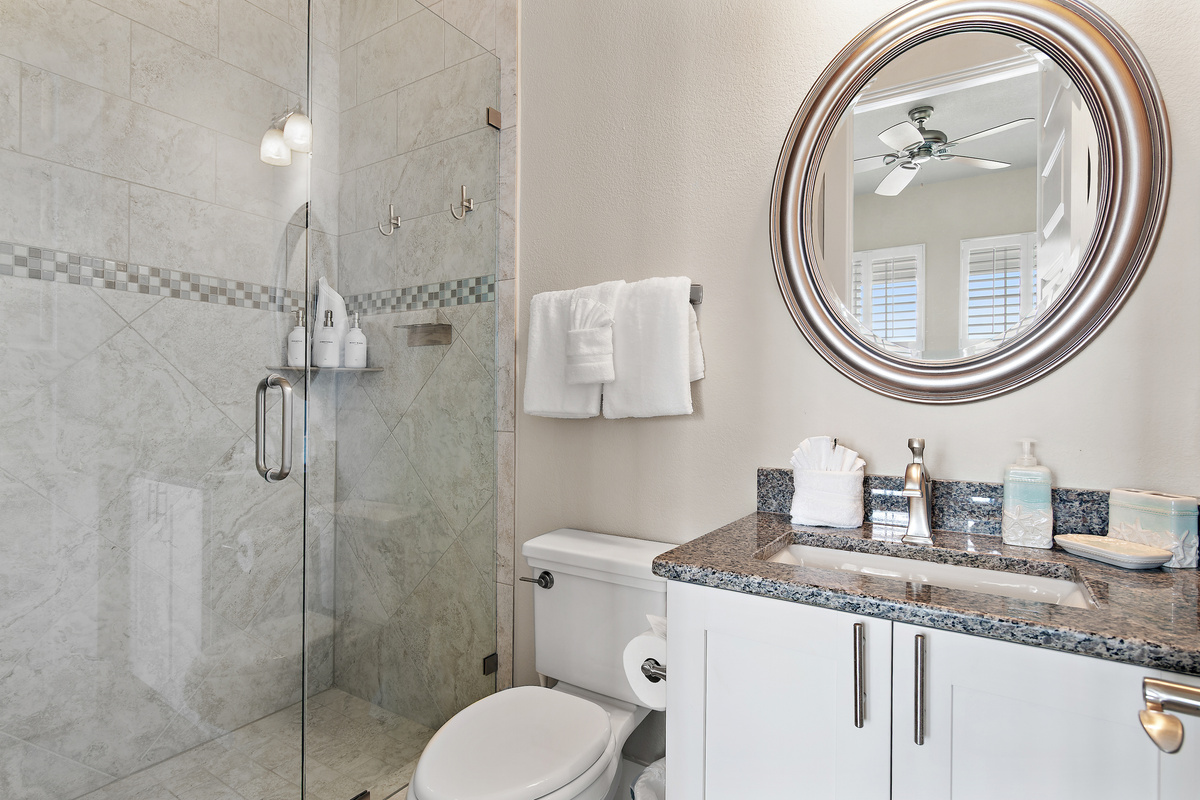 Bright, spacious bathroom with a walk in shower, generous vanity, and elegant coastal details.
