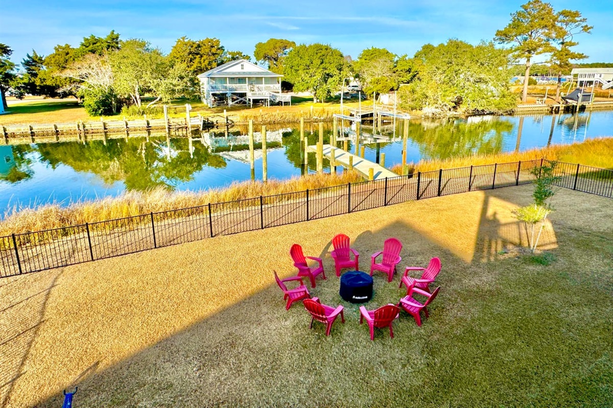 Private backyard dock with boat lift and fillet table, fenced-in backyard, fire pit with Adirondack chairs, hammocks, propane grill, picnic table, outdoor shower, expansive waterfront back deck with table and seating, neighborhood boat ramp and dock