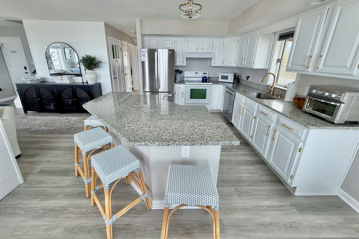 Enjoy the convenience of this bright, modern kitchen. With ample counter space and stylish seating, it is the perfect spot for friends and family to gather, chat, and relax together during your dream coastal getaway.