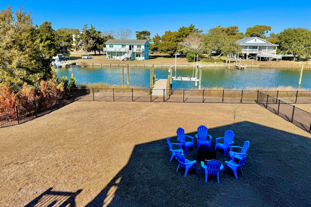 Private backyard dock with boat lift and fillet table, fenced-in backyard, fire pit with Adirondack chairs, hammocks, propane grill, picnic table, outdoor shower, expansive waterfront back deck, neighborhood boat ramp and dock