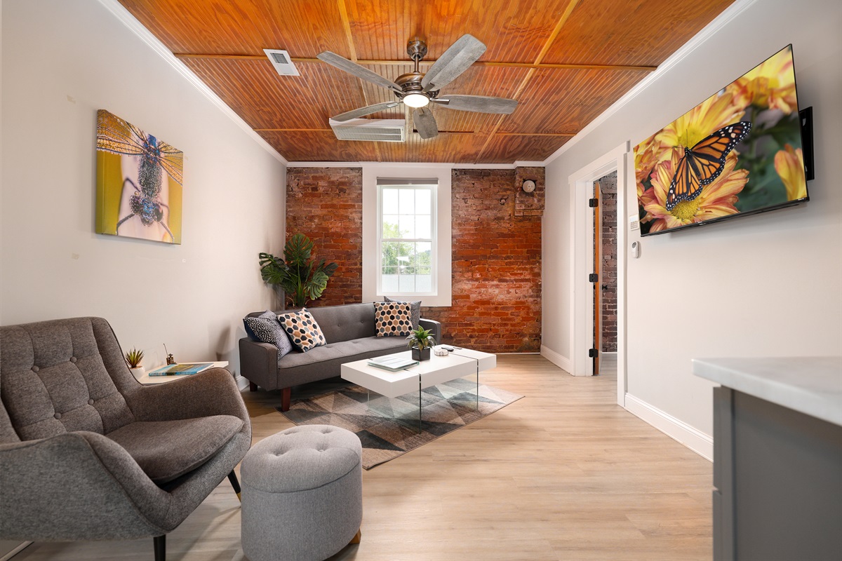 Living Room with exposed brick wall, large TV, beverage area with refrigerator