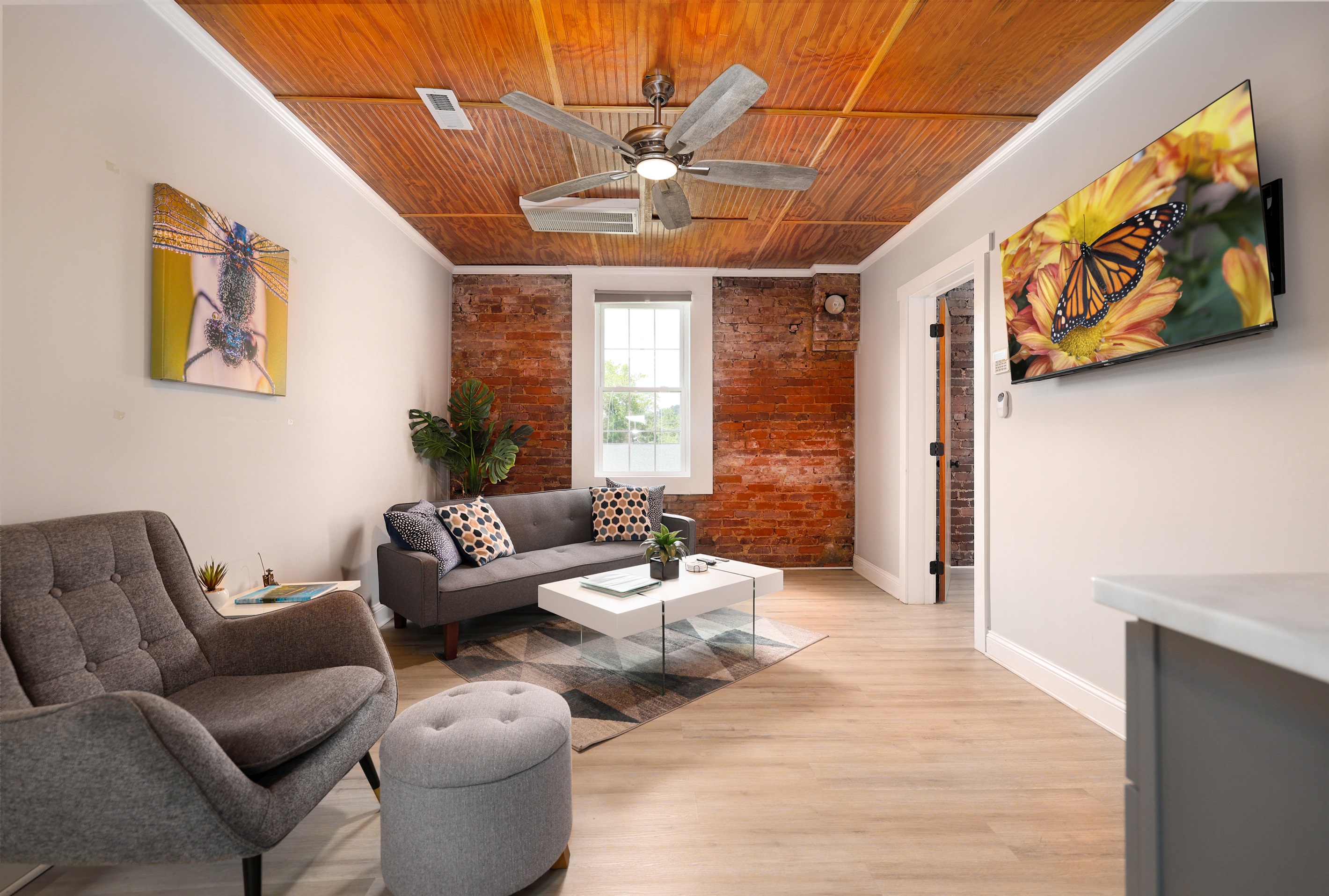 Living Room with exposed brick wall, large TV, beverage area with refrigerator