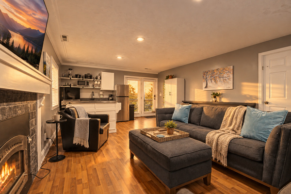 Living room with a stone fireplace, smart TV and sleeper sofa. Cozy family gathering space in your Sevierville, TN cabin rental.