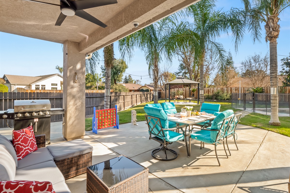 Covered patio with comfortable seating, outdoor dining table, and plenty of yard space for kids to run and play. Lawn games and open green space make it perfect for family time outside.