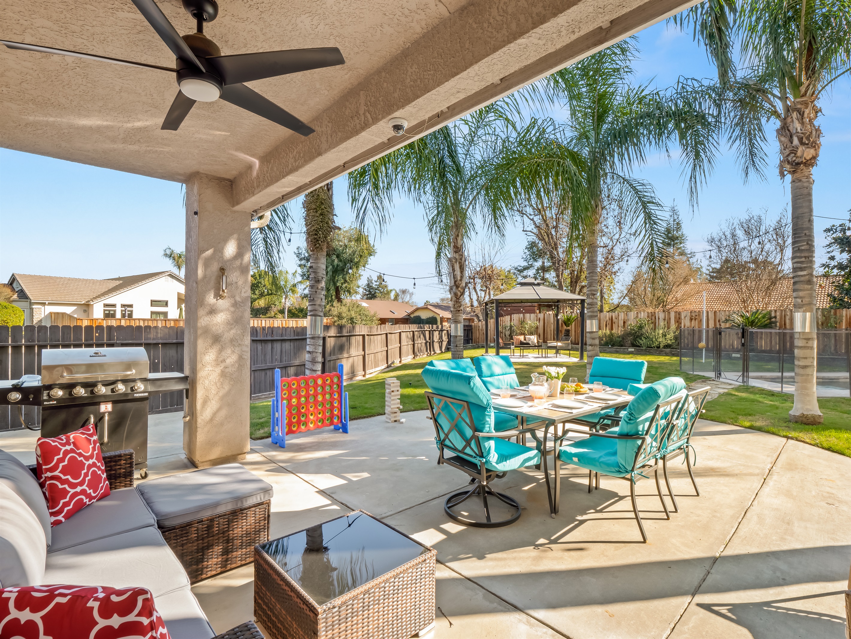 Covered patio with comfortable seating, outdoor dining table, and plenty of yard space for kids to run and play. Lawn games and open green space make it perfect for family time outside.