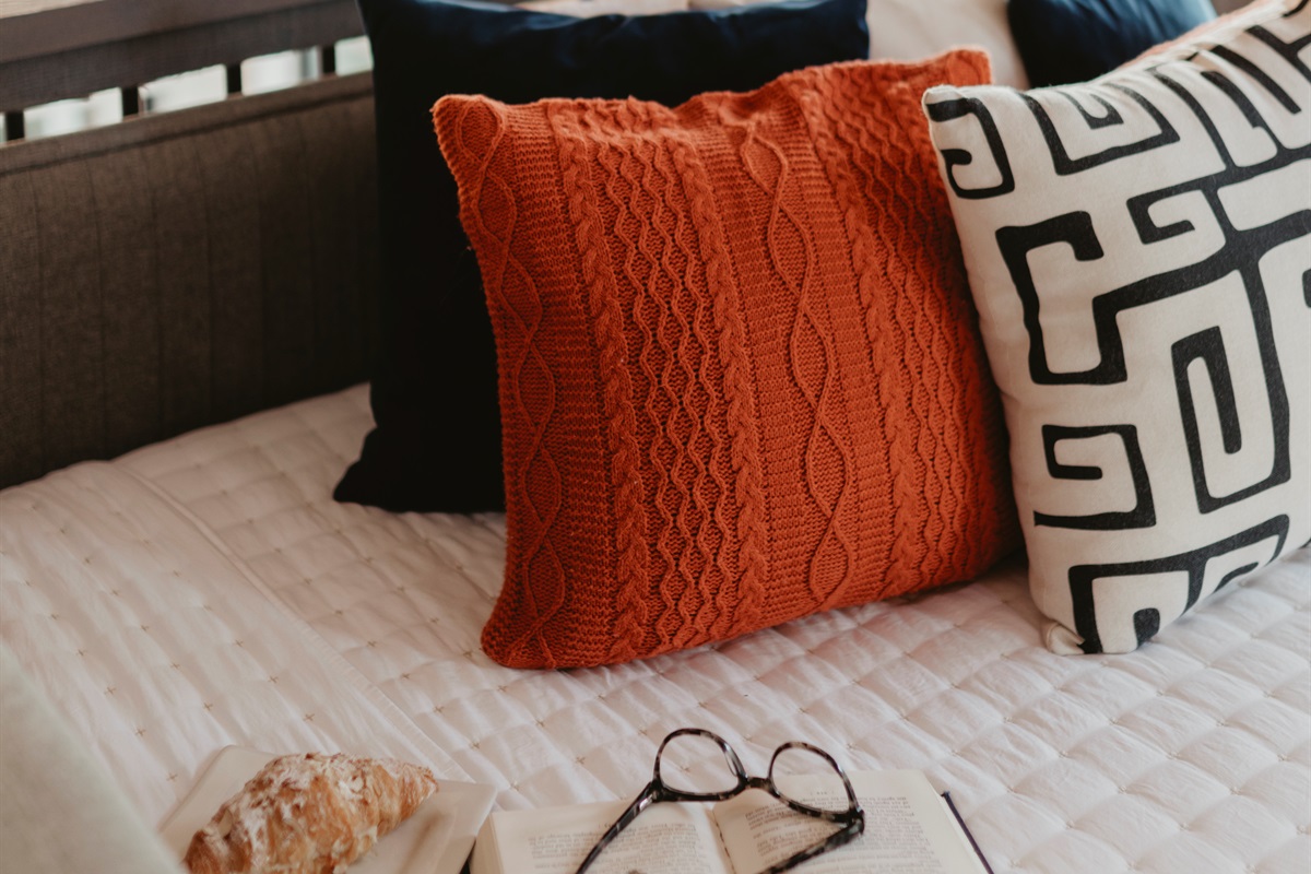 A cozy detail shot with textured pillows and soft linens. Perfect for curling up with a book, a pastry, or just soaking in quiet cabin mornings.