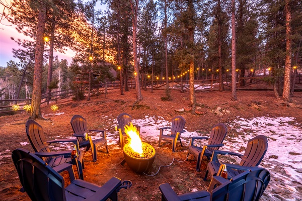 🔥✨ Evening firepit glow—Adirondack chairs under twinkle lights, pine trees all around, and plenty of room for s’mores, stories, and stargazing 🌲🌌
