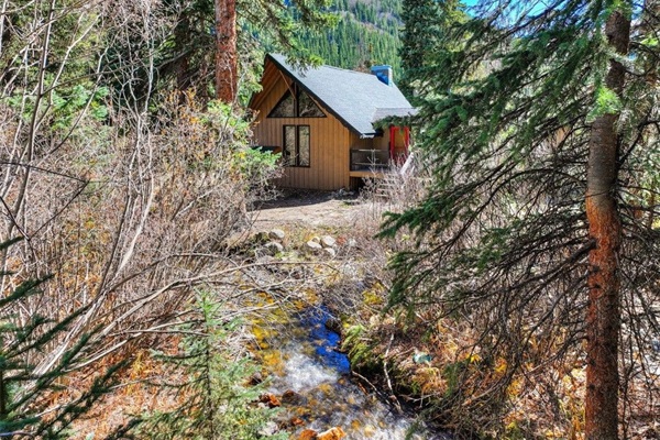 Escape to your cozy cabin retreat, where towering trees, a peaceful stream, and mountain views surround you in nature and make it all yours to unwind.
