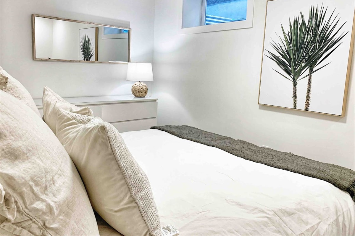 Primary bedroom with comfortable queen bed, soft lighting, and simple Scandinavian styling.