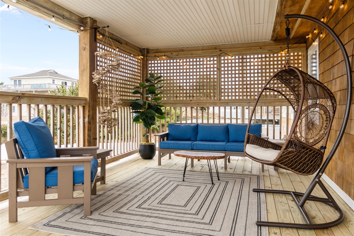 Screened-in porch with comfortable seating and a hanging chair for lounging.