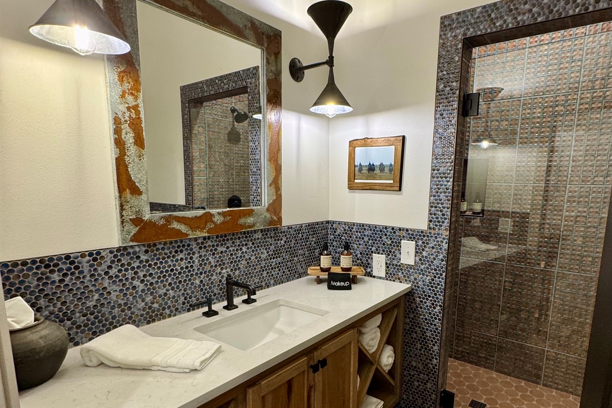 Cutter's Quarters Bathroom #1 wide — walk-in tile shower, designer vanity, and modern Western finishes. One of six private bathrooms across the entire property.