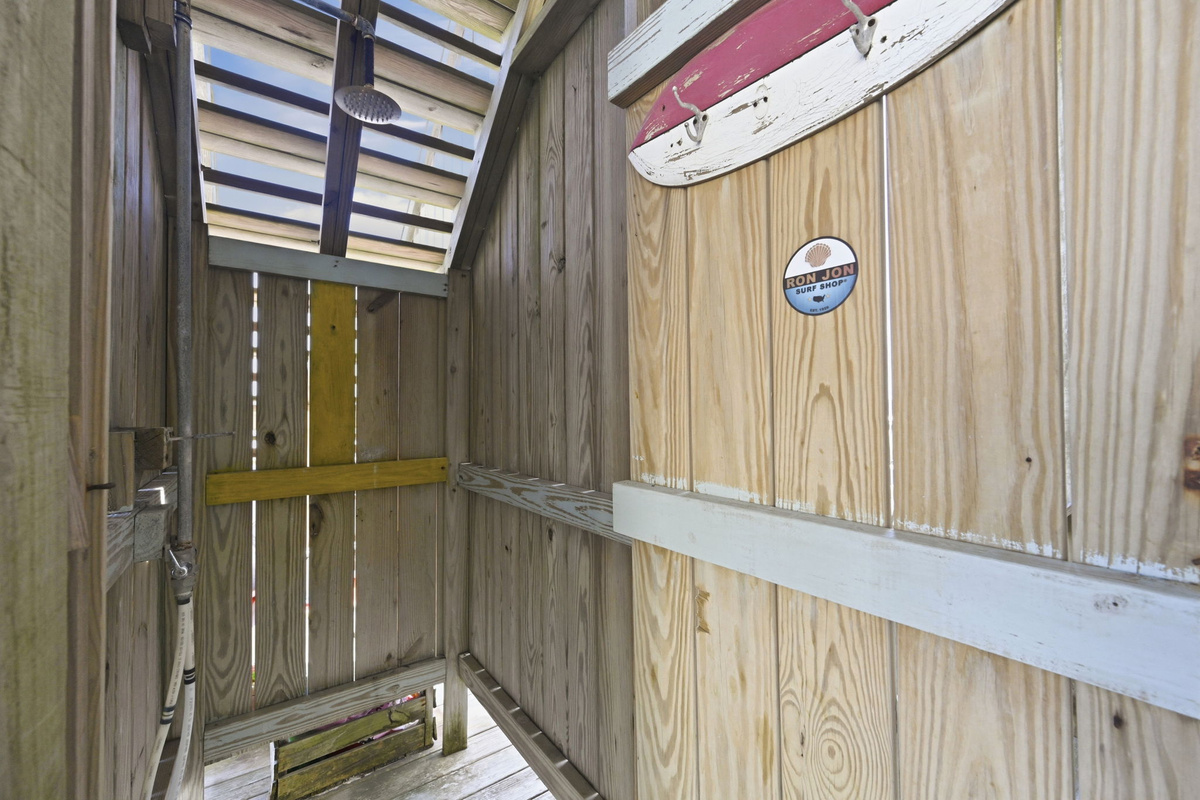 Outdoor enclosed beach shower area with surf-themed decor