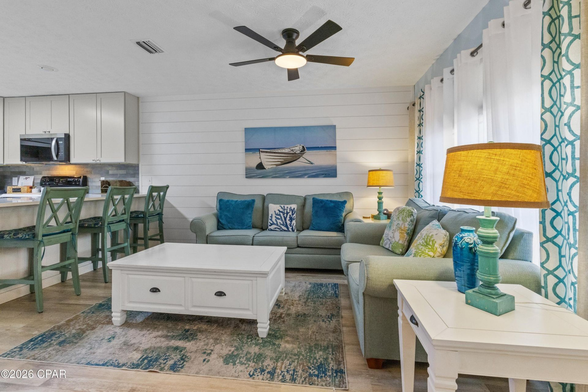 Bright coastal living space perfect for relaxing after a beach day! Enjoy comfortable seating, Smart TV entertainment, and an open layout designed for family time.