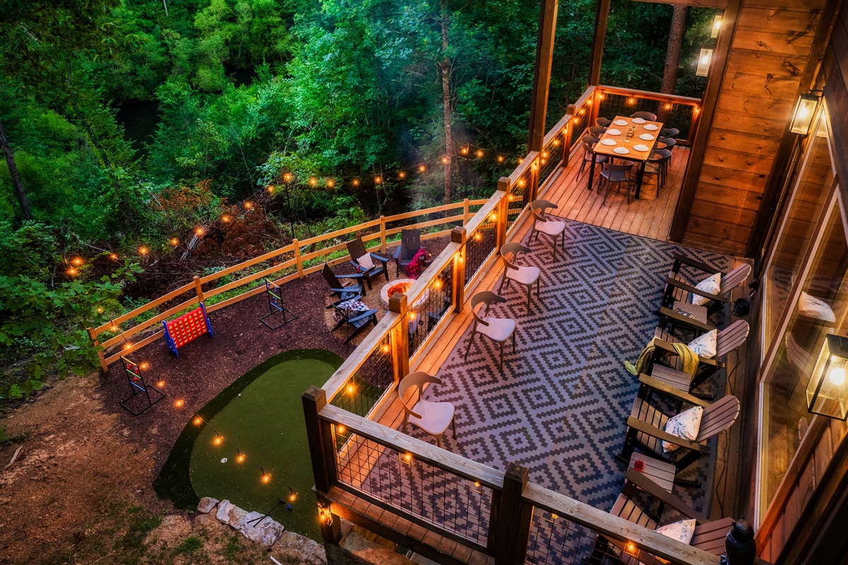 Luxury cabin with multiple decks with string lights, hot tub, and backyard with fire pit, mini golf, and outdoor games