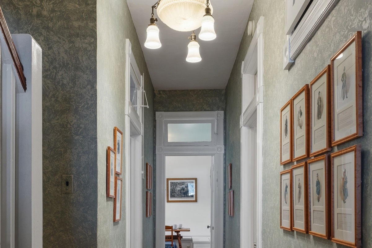 Main floor hallway lined w/ framed artwork & soft lighting