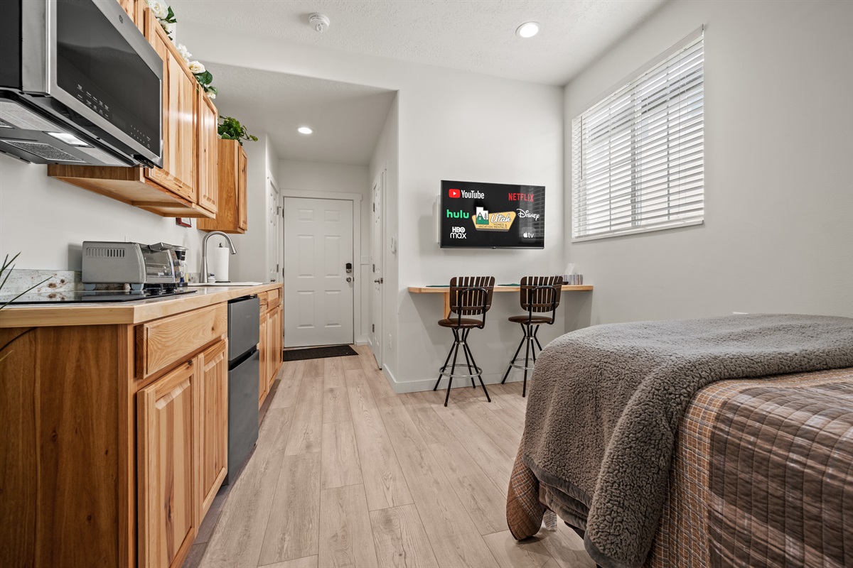 Spacious studio featuring a large Smart TV, kitchenette, and breakfast bar.