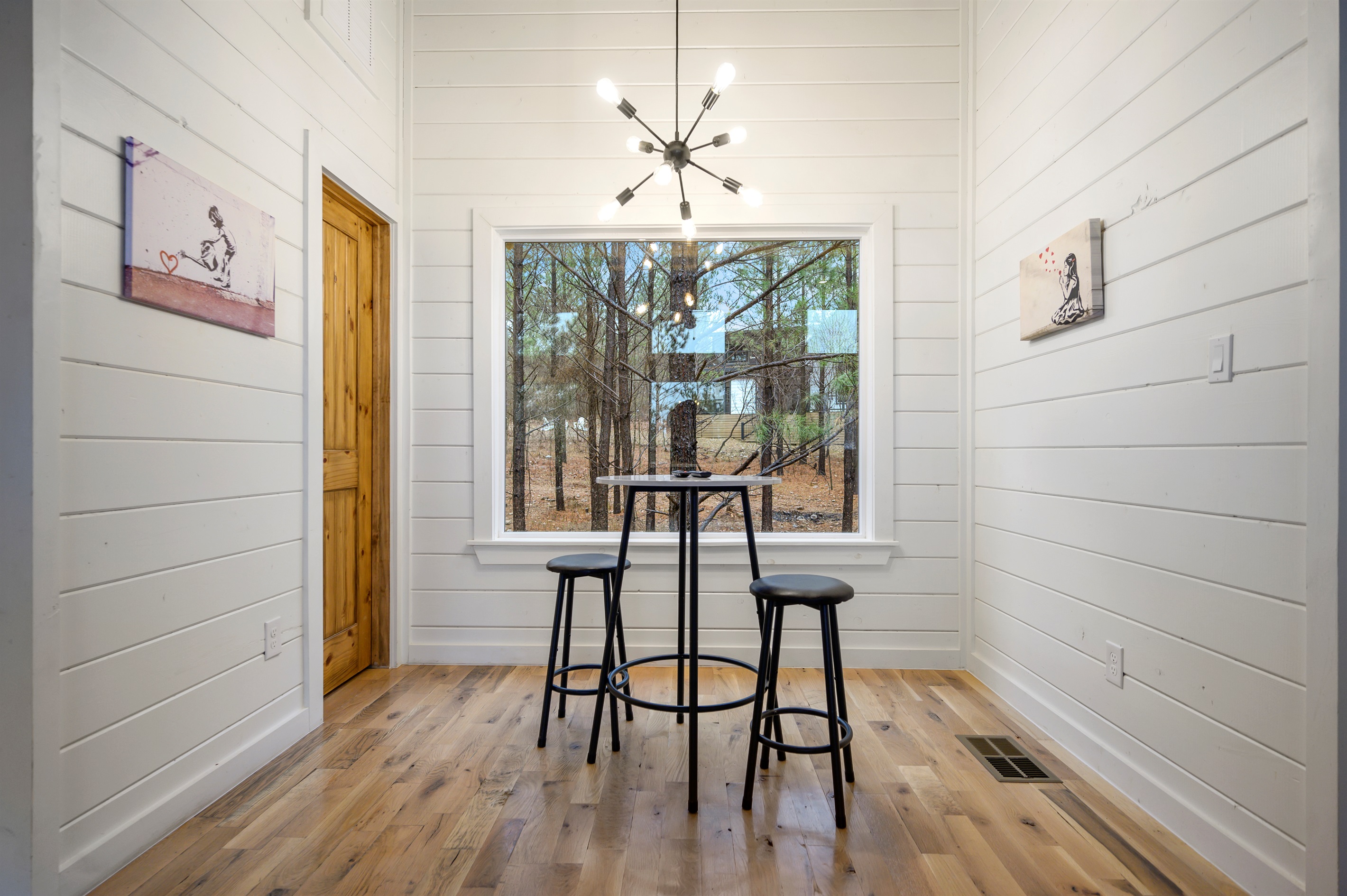 A quiet seating nook for two with a high table and chairs placed in front of a large window — the perfect spot to enjoy morning coffee while taking in the peaceful view. ☕