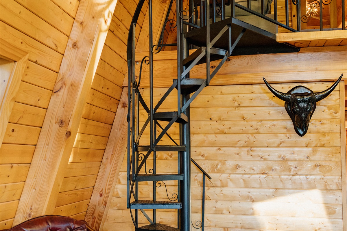 The striking spiral staircase leads to Poppywood Pines' loft, showcasing this gothic western A-frame's unique architecture. Authentic details and dramatic design elements create an unforgettable Show Low vacation rental experience in the White Mountains.