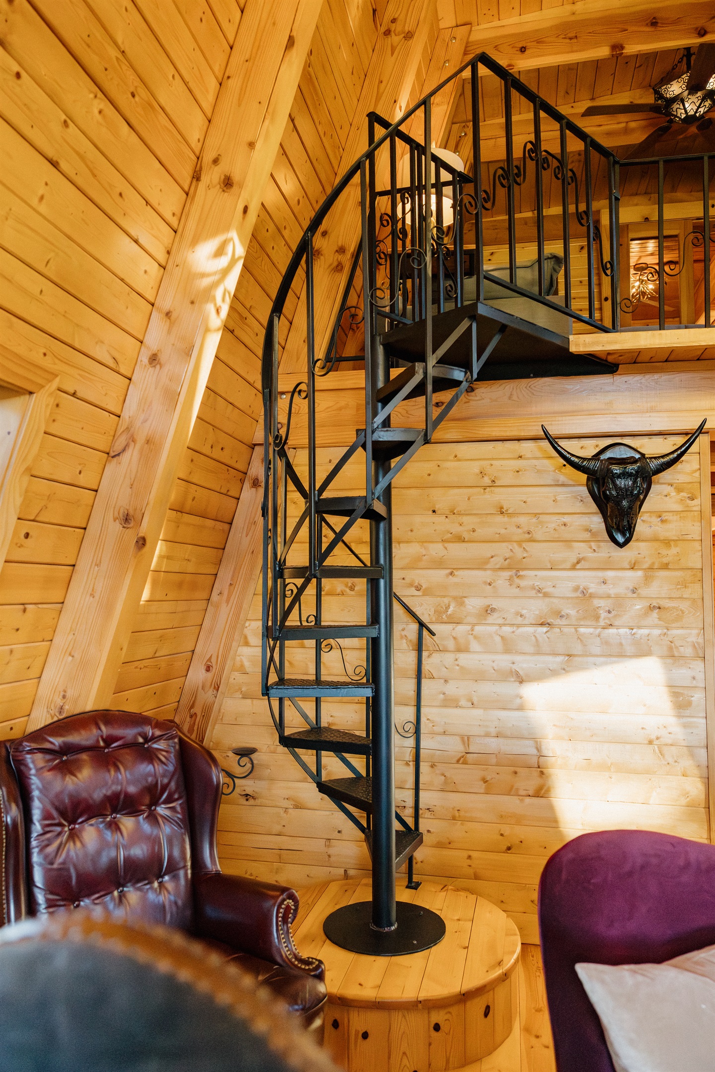 The striking spiral staircase leads to Poppywood Pines' loft, showcasing this gothic western A-frame's unique architecture. Authentic details and dramatic design elements create an unforgettable Show Low vacation rental experience in the White Mountains.