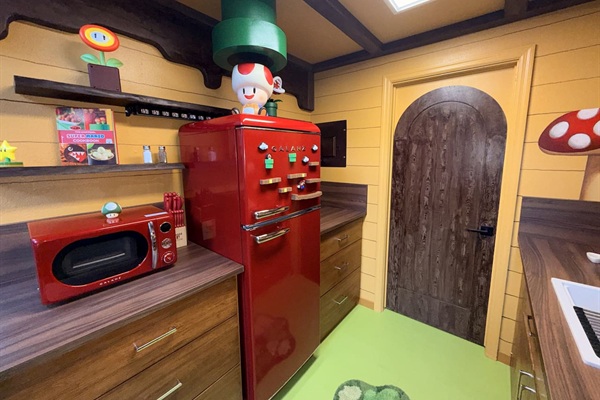 Retro red fridge and microwave corner in our Nintendo-inspired kitchen at Mario's Mini Mansion near Orlando, FL. Green pipe decor "toadstool cafe" vibe walls, and playful Super Mario accents bring joy to every cooking moment.