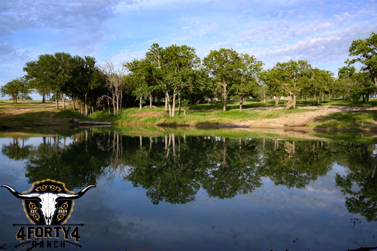 A view of the pond and game center that features a pickleball court