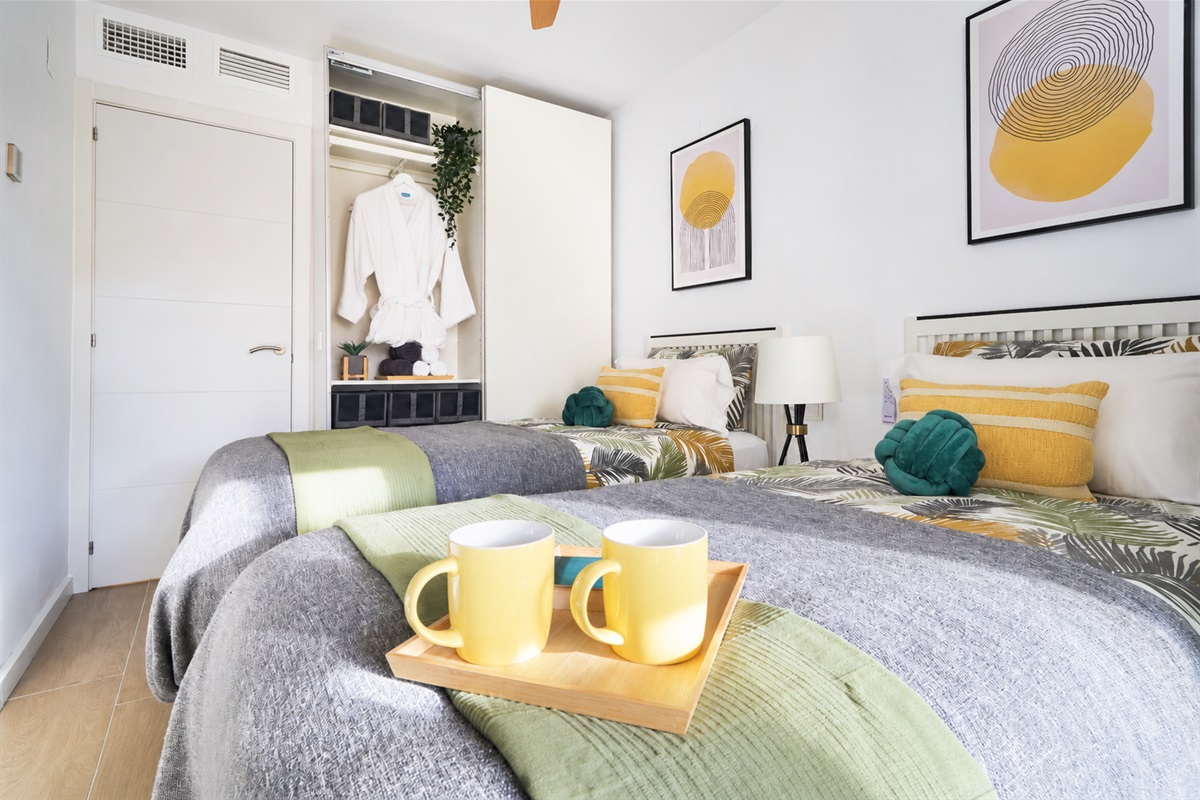 Bright and calming twin bedroom with tropical tones, soft linens, and direct access to the terrace - perfect for relaxed mornings and restful nights.