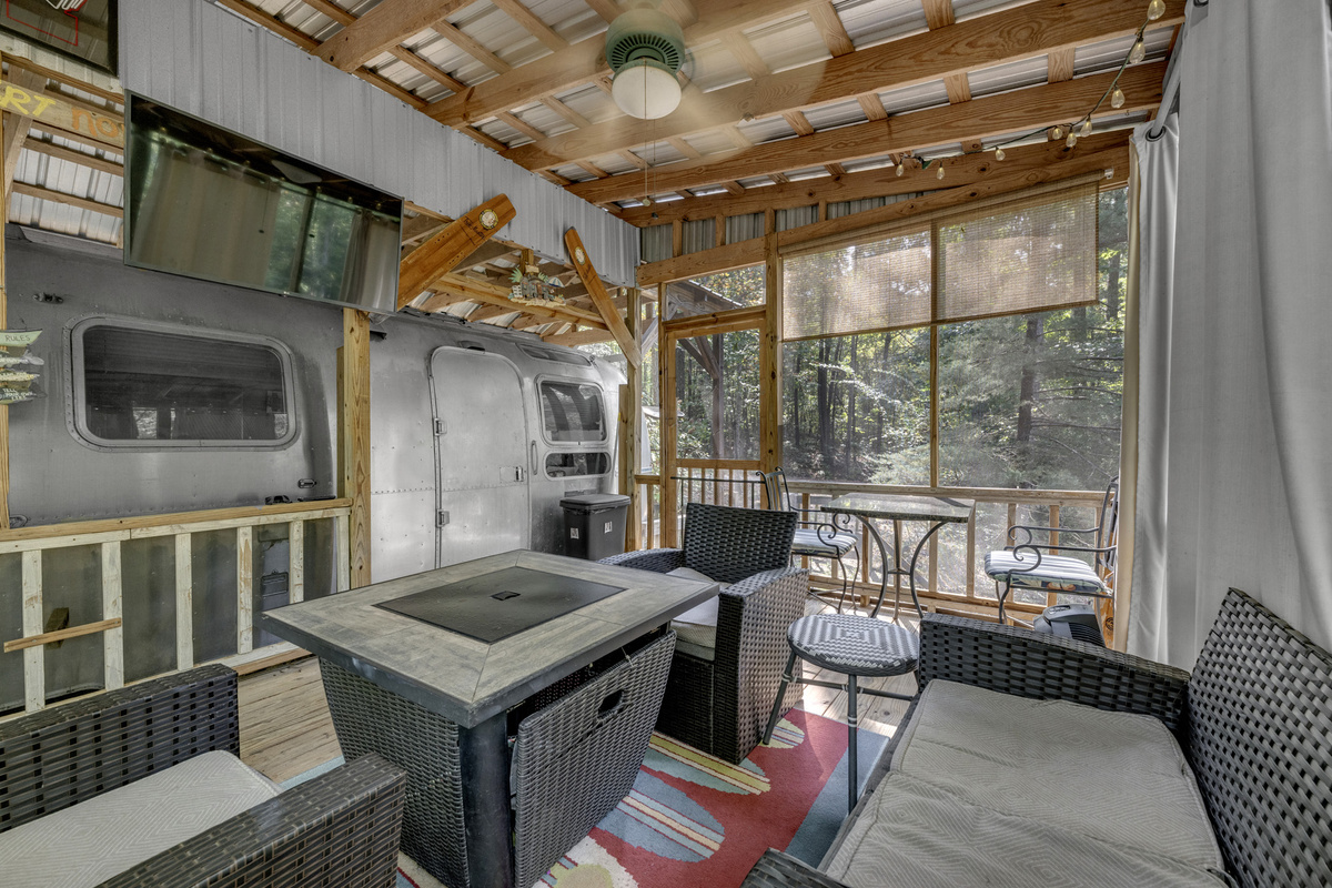 A screened-in outdoor living room made for meals, games, and relaxing after a day on the lake