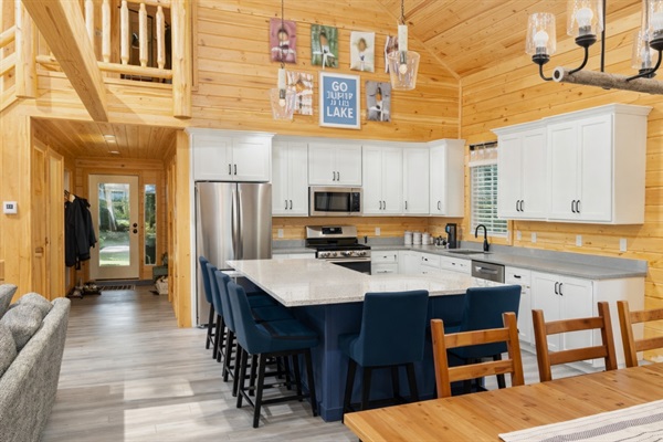 Fully equipped modern kitchen with new appliances, gas range, stone countertops, and large island seating