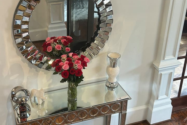 Chic entryway vignette featuring a mirrored console table, statement round mirror, and fresh florals—adding a refined, welcoming touch to the home’s thoughtfully designed interior.
